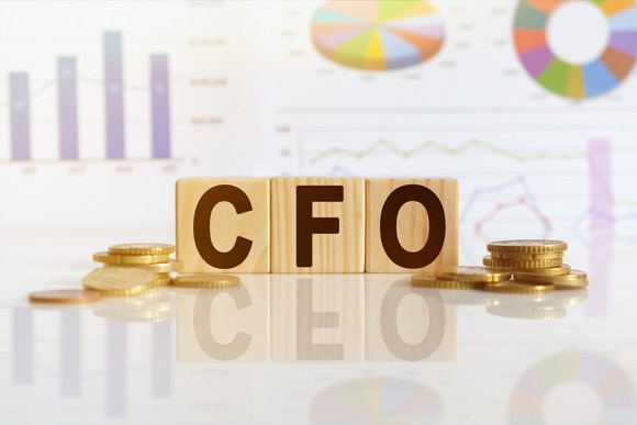 Blocks spelling "CFO" surrounded by coins and financial charts.