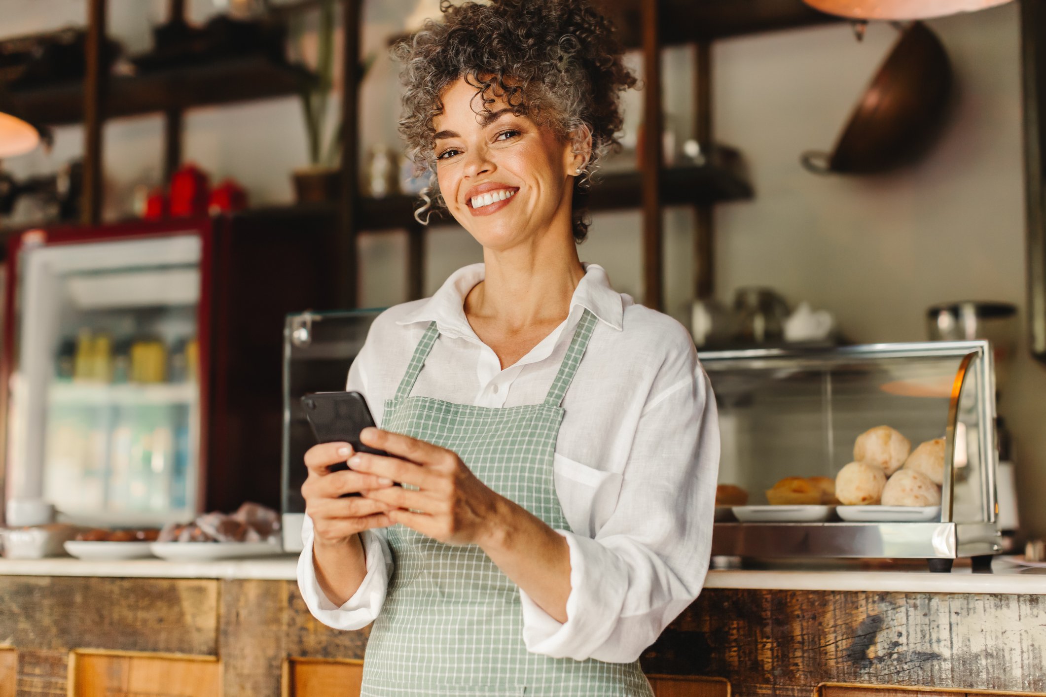 Worker behind restaurant counter with smartphone.