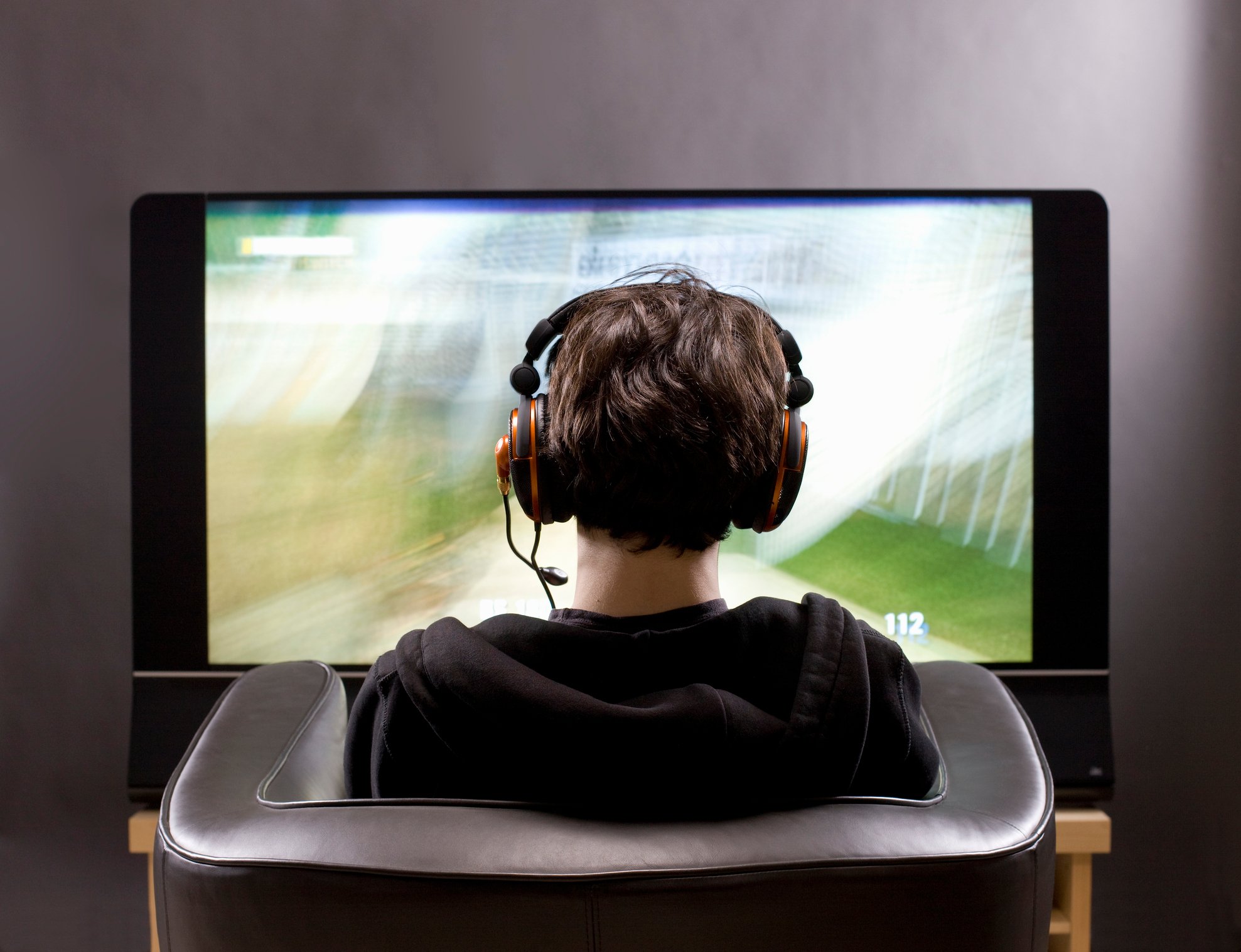 A person sitting in front of a screen and wearing a headset.