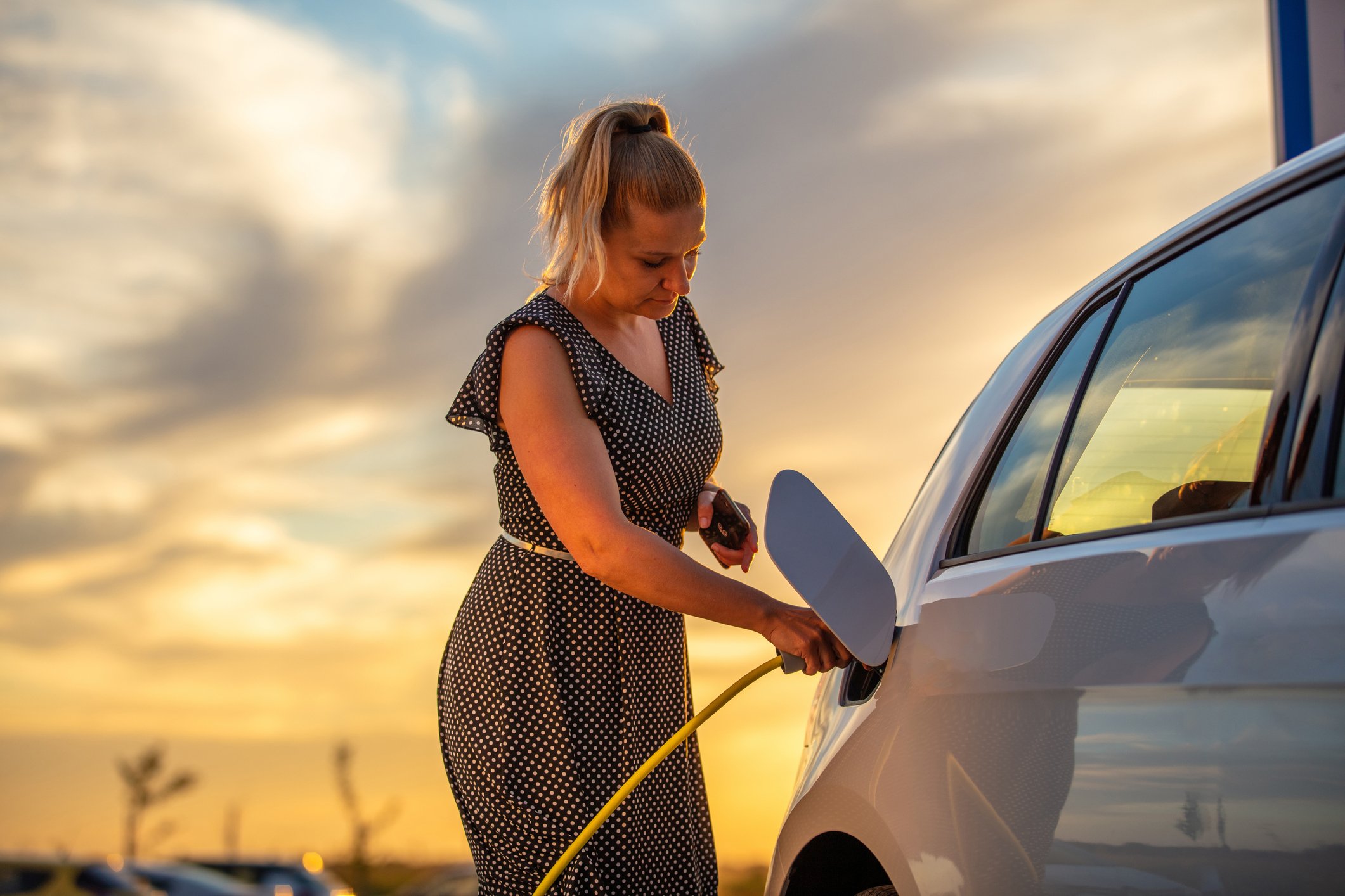A person is plugging a charger into an electric vehicle. 