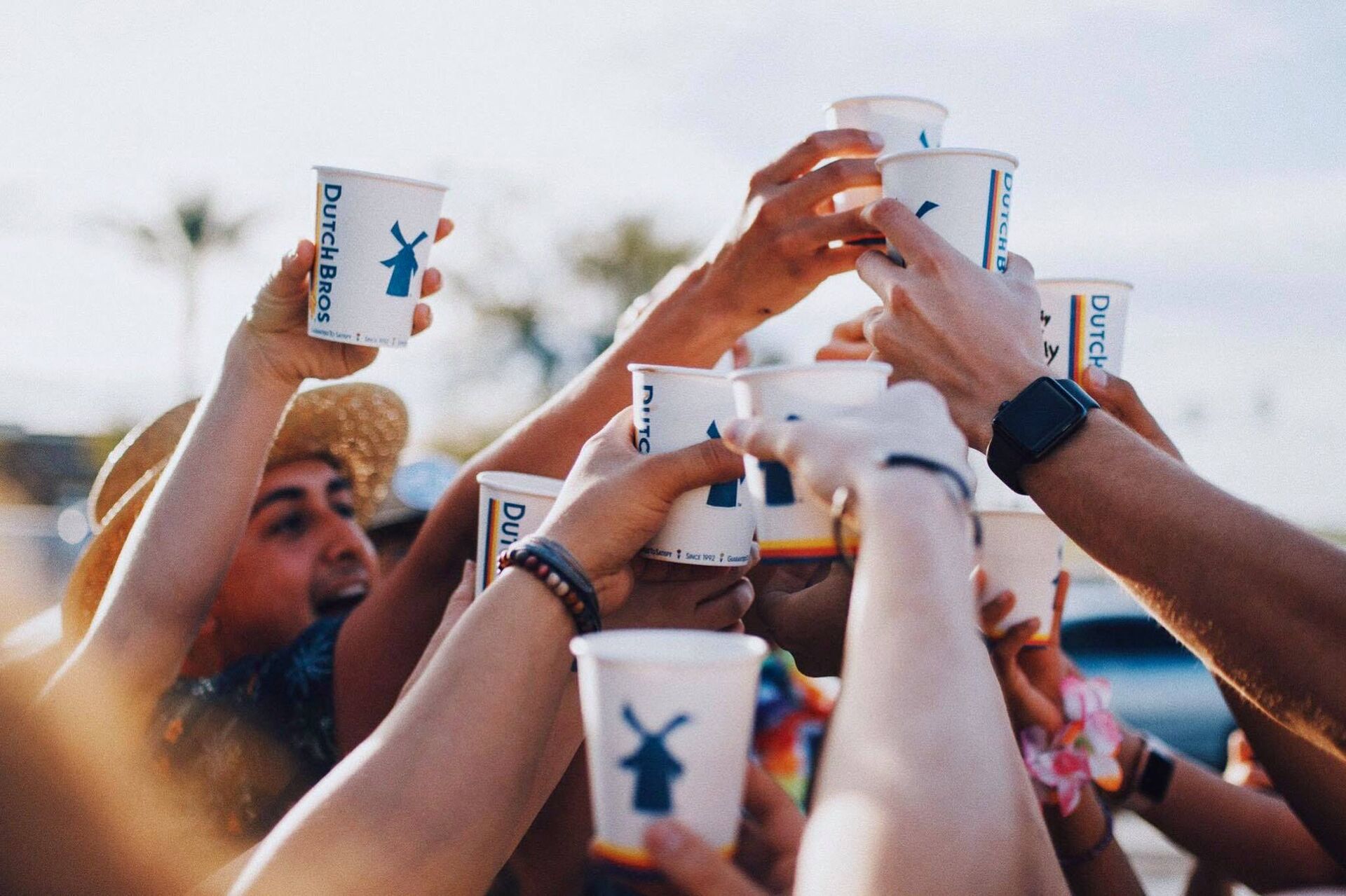 People toasting with Dutch Bros. coffee cups.
