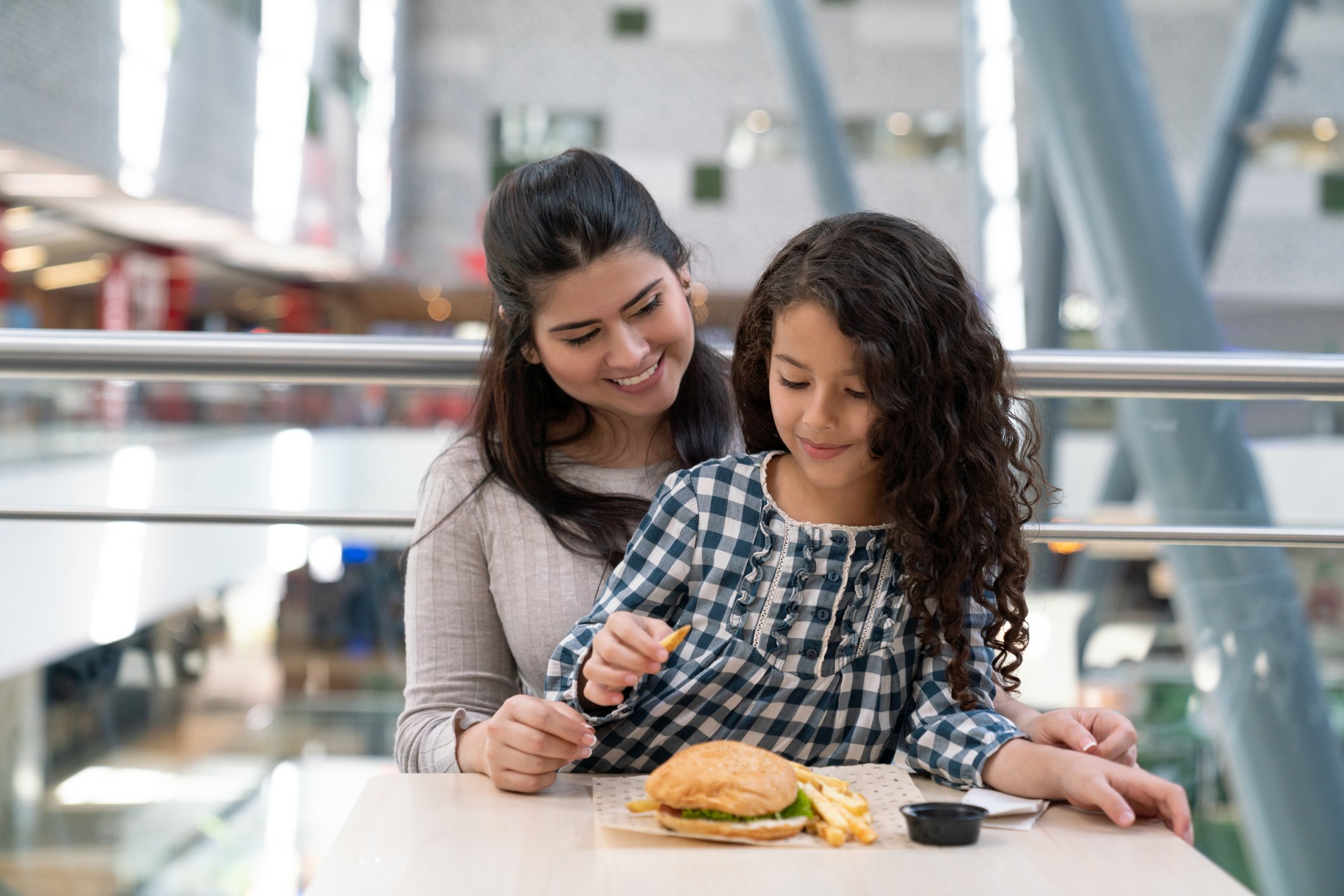 Two people eating a burger and fries.