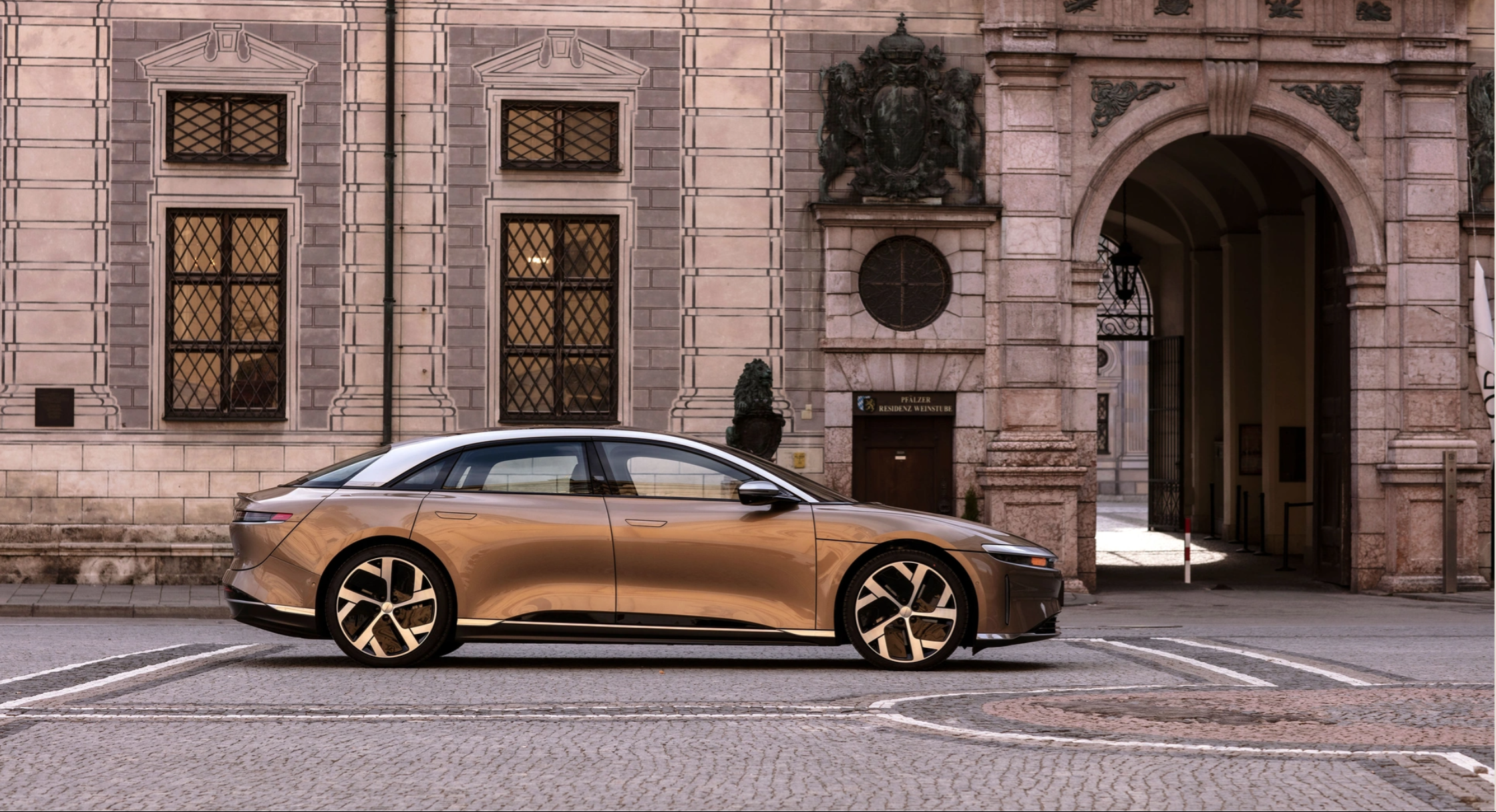 Lucid Air sedan parked on cobblestones outside European studio.