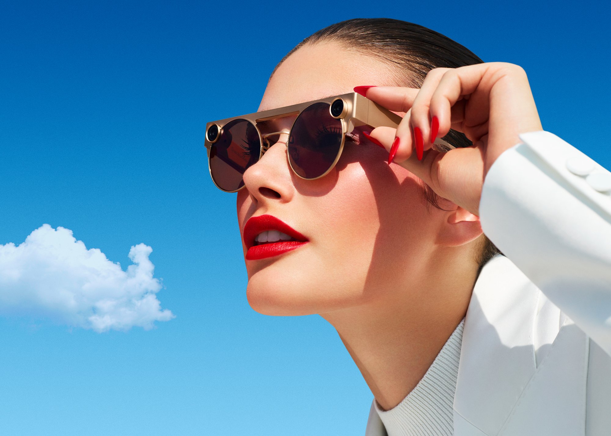 Snap's Spectacle 3 augmented reality glasses are seen on a model's face with blue skies in the background