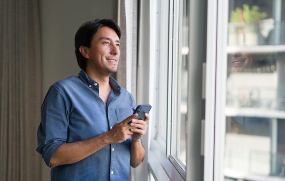 A smiling person holding a cell phone.