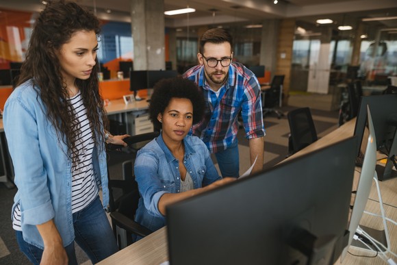 Three people in an office all looking at a computer screen.
