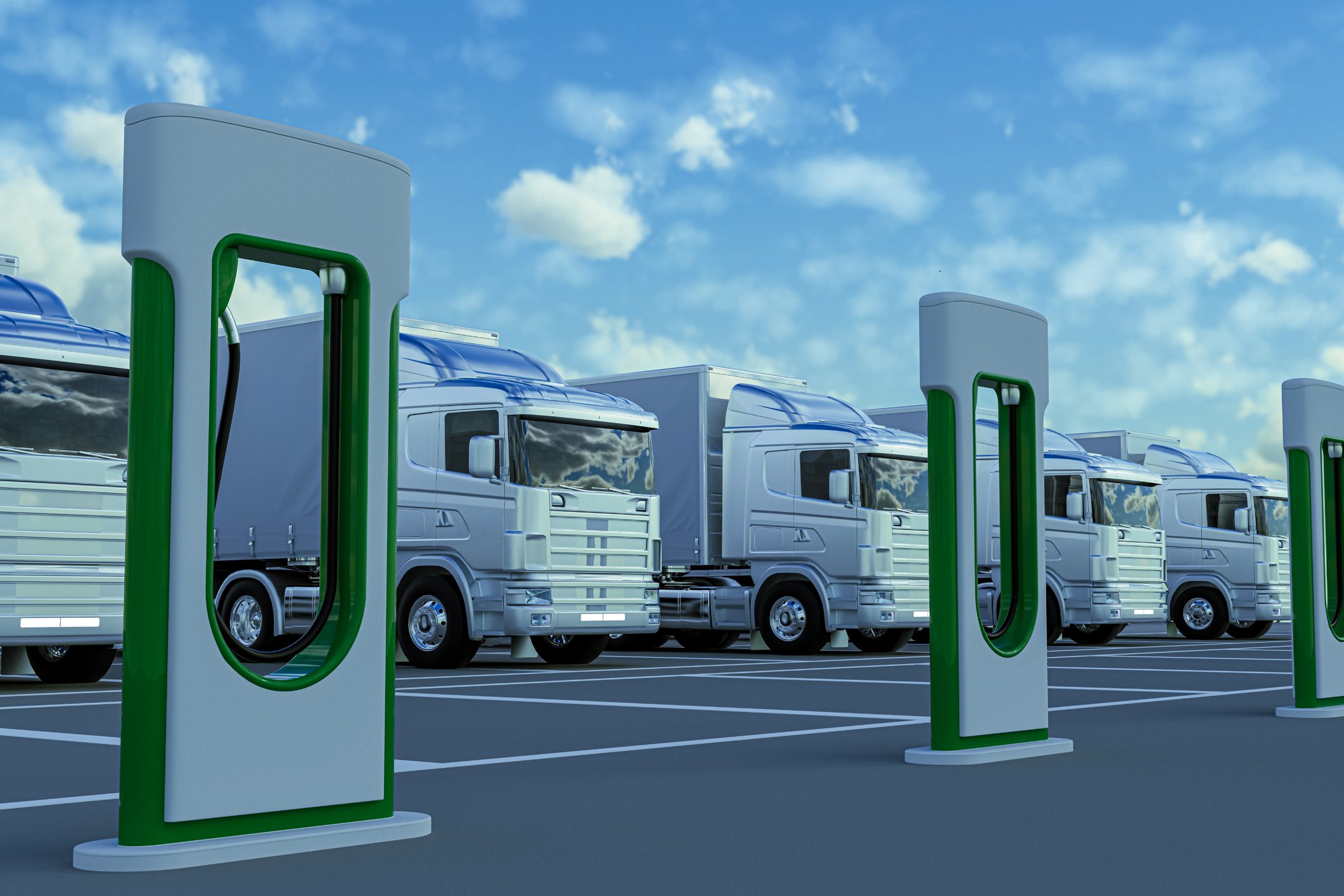 Row of electric trucks at a charging station.