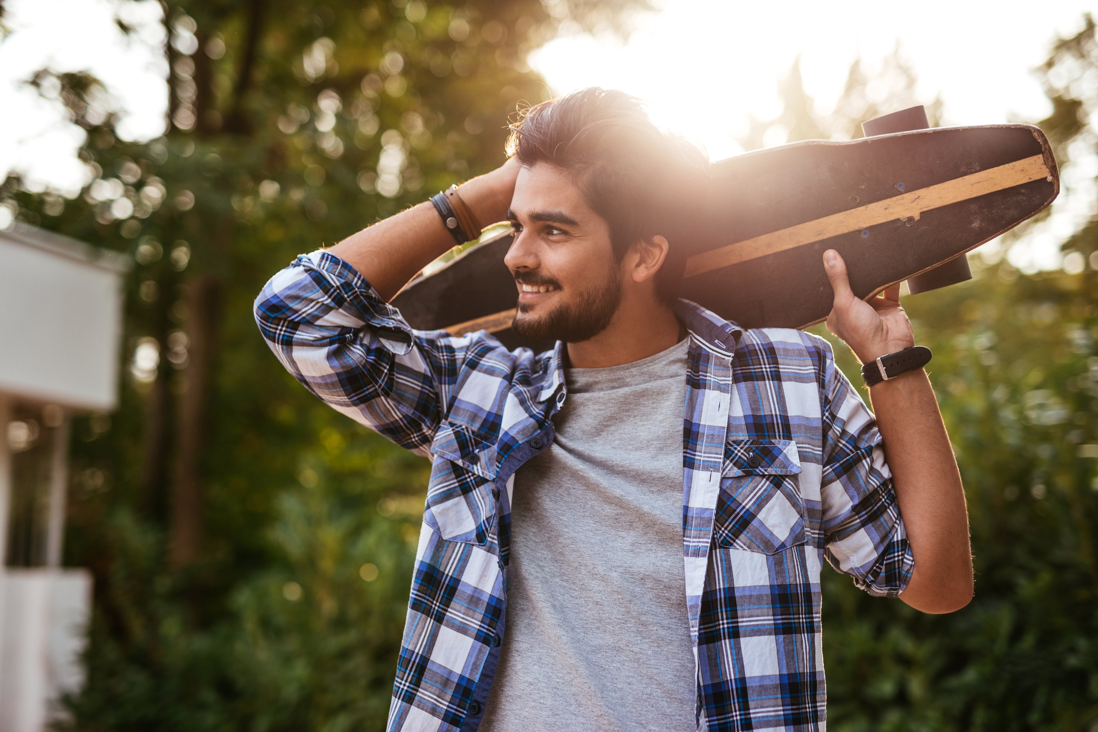 A young person in a stylish plaid shirt holding a skateboard.