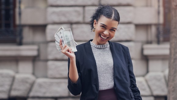 A person smiles while flashing cash a handful of cash.