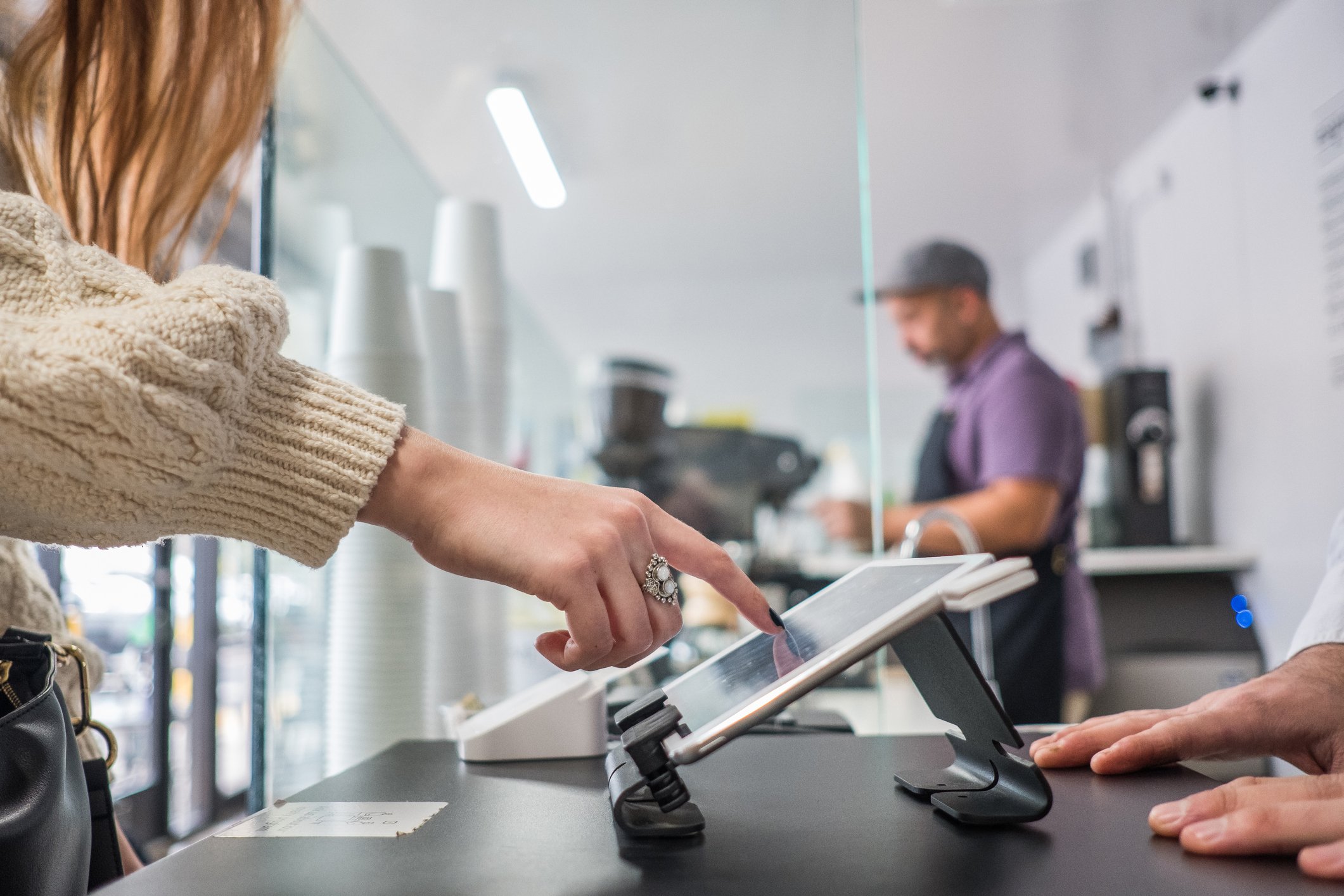Person pressing a tablet point-of-sale terminal in a shop.