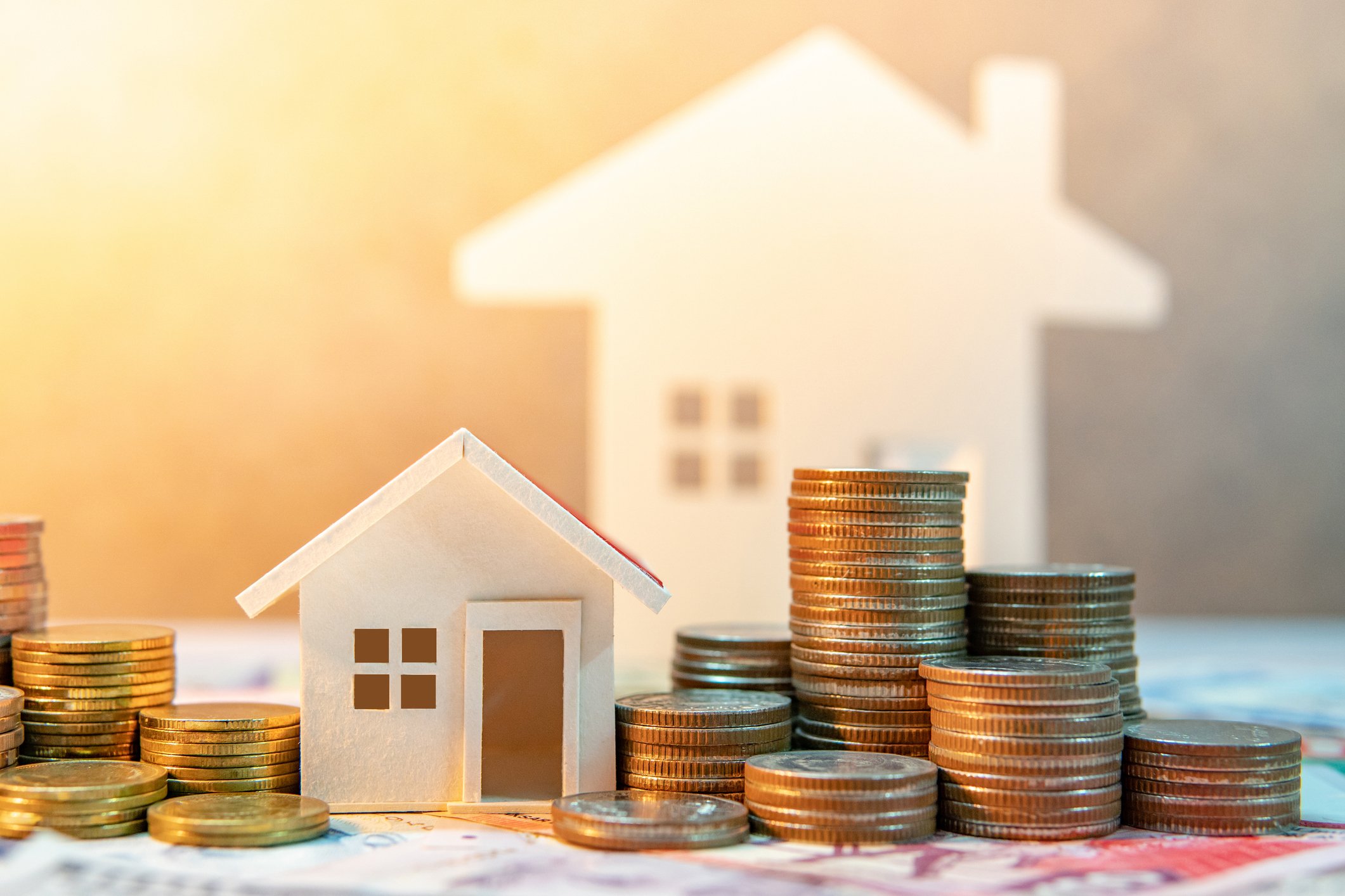 Stacks of coins next to small houses.