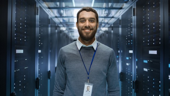 Data engineer standing between two stacks of servers.
