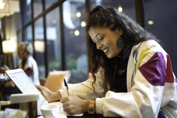 A person uses a tablet in a coffee shop.