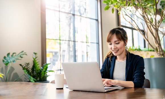 An investor smiles and works at a laptop in a spacious office.