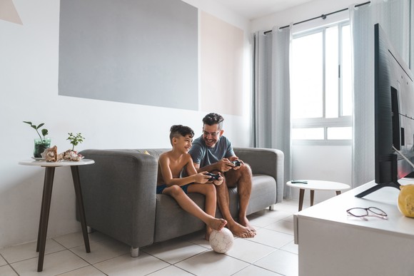 Two people sitting on a couch playing a video game.