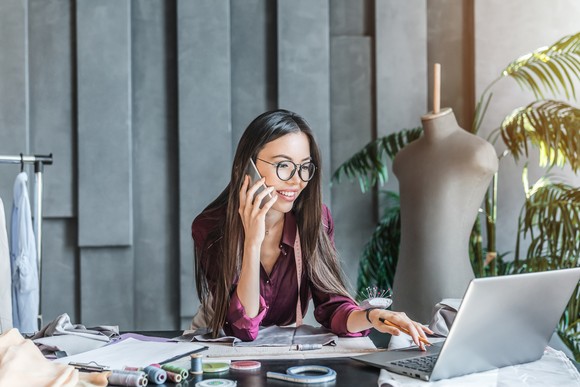 fashion designer using laptop and phone.