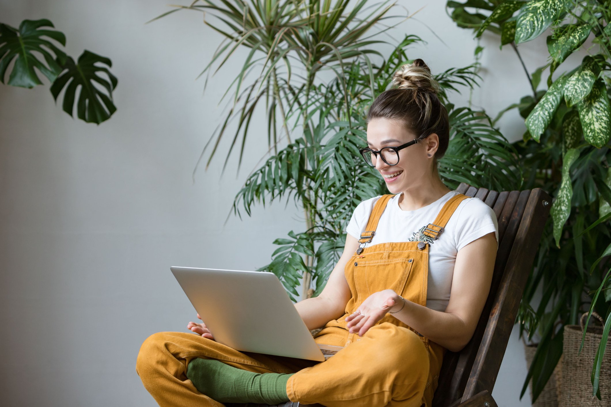 A consumer surrounded by plants buys online from a laptop.