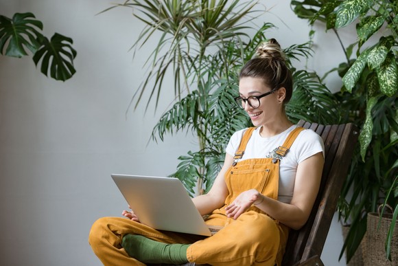 A consumer surrounded by plants buys online from a laptop.