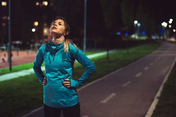 Tired jogger taking a break on a footpath at night.