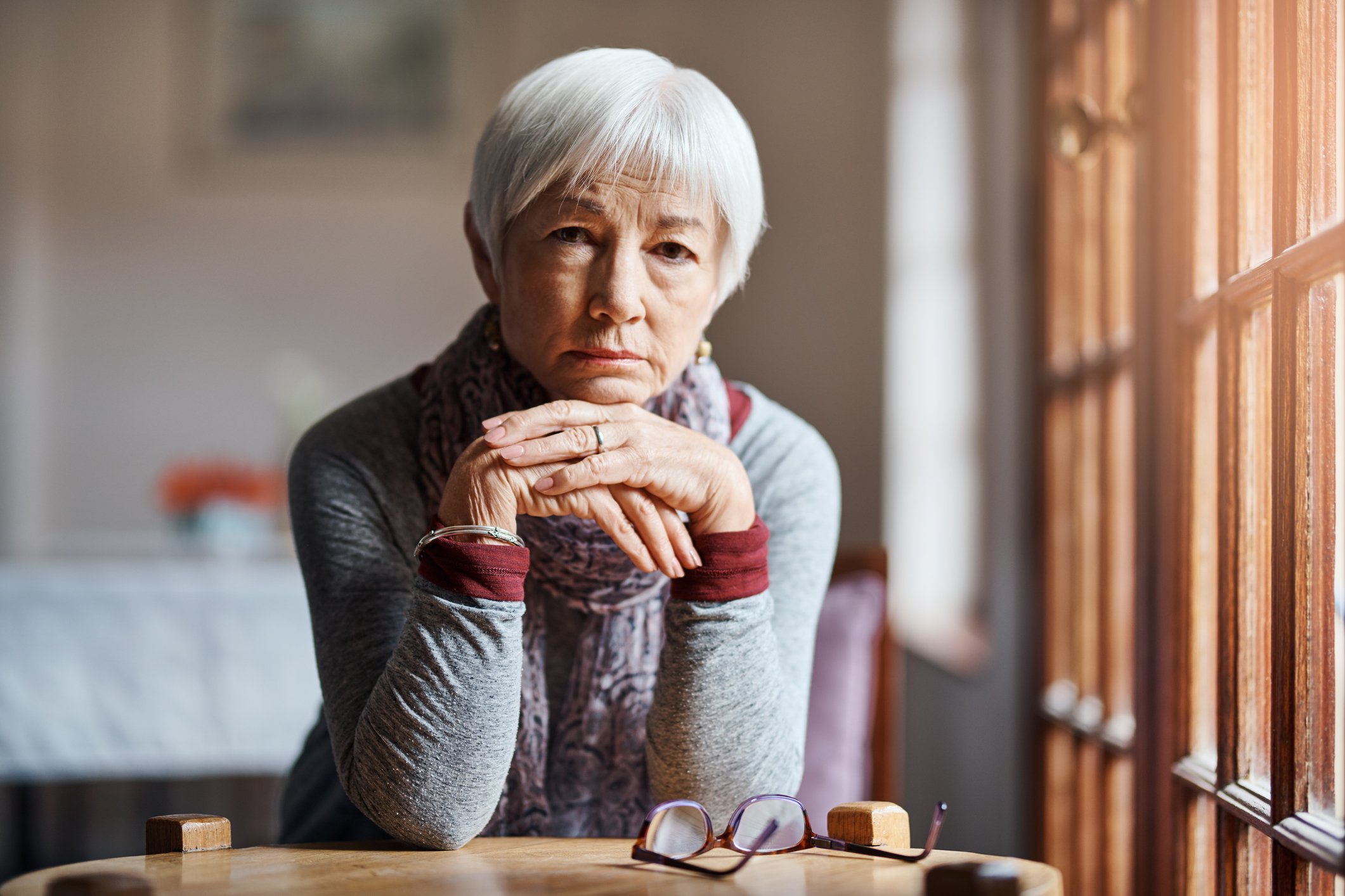 Regretful-looking senior sitting at table.