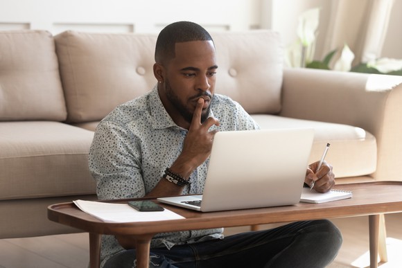 Person sitting on the floor thinking about what's on the computer screen. 