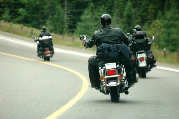 Motorcycle riders on curve in road from behind.