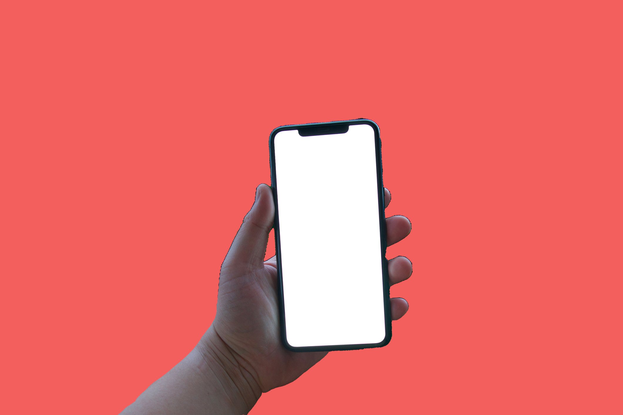 Hand holding a blank smartphone against a red background.