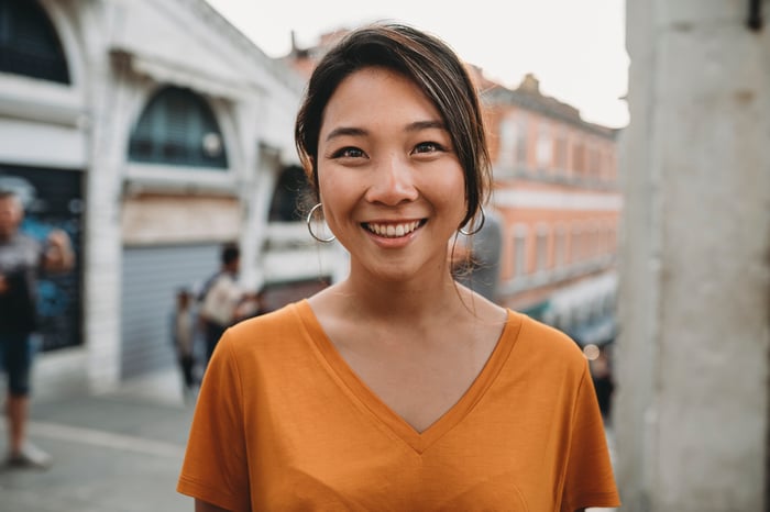 Someone is outdoors in a city, smiling.