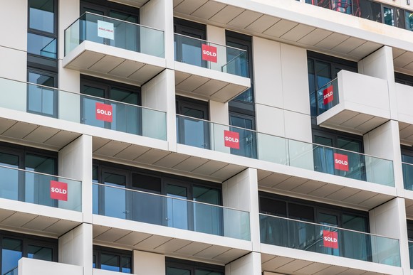 Condo building with sold signs on multiple balconies.