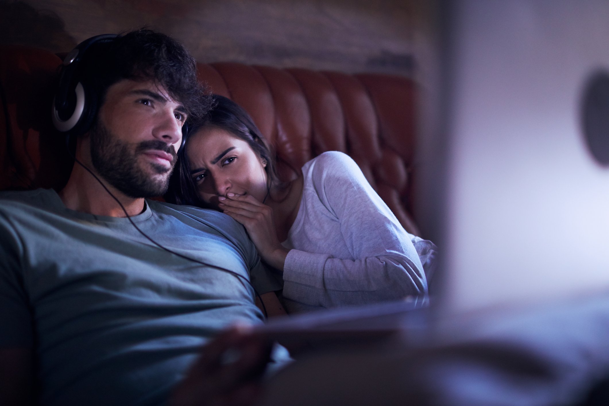 Two young people seated on a couch and watching some entertainment.