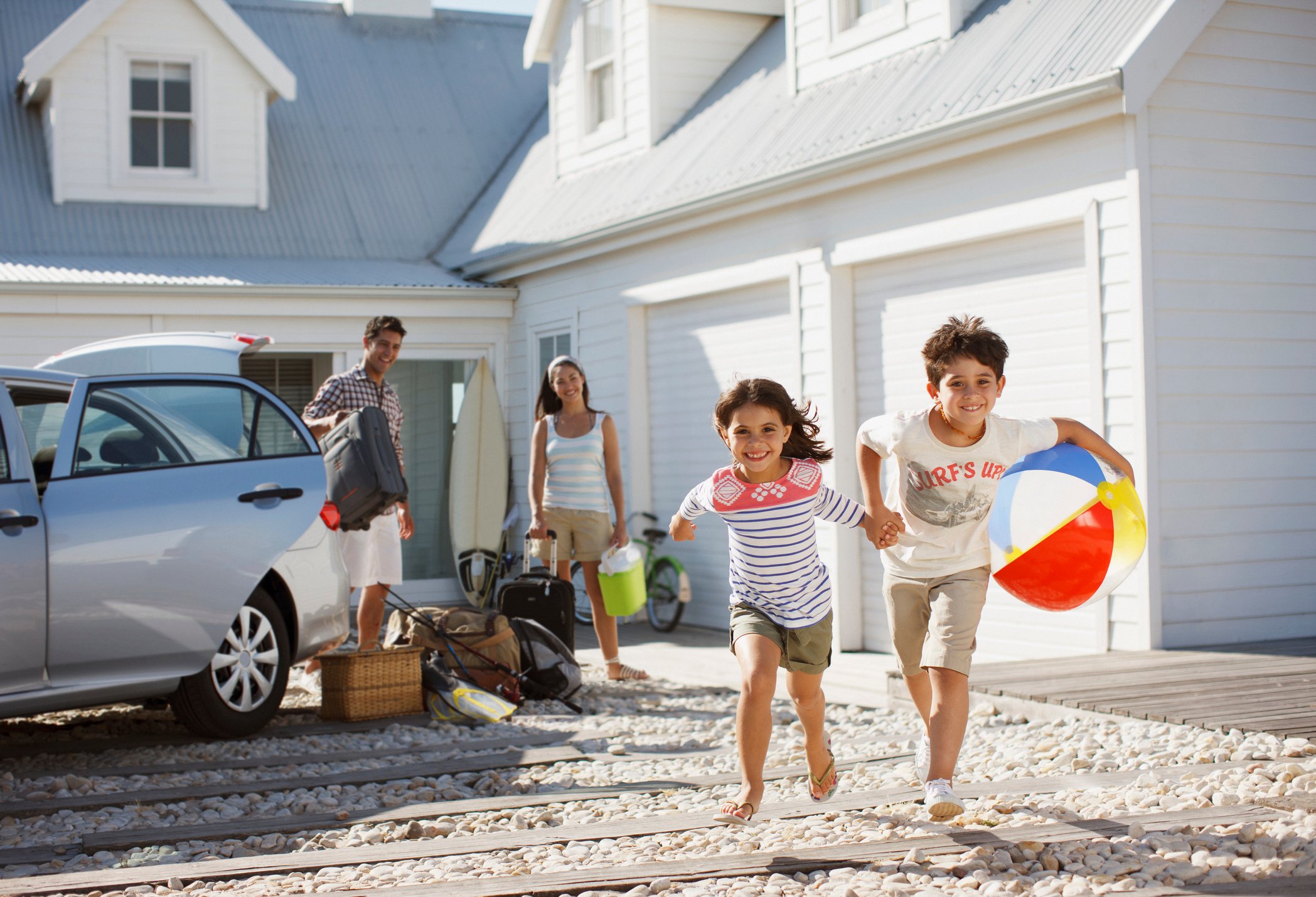 Kids running outside a beach house as parents observe. 