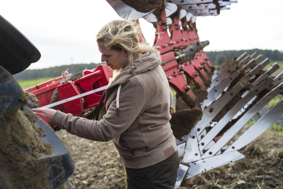 A person fixing a plow on a farm.