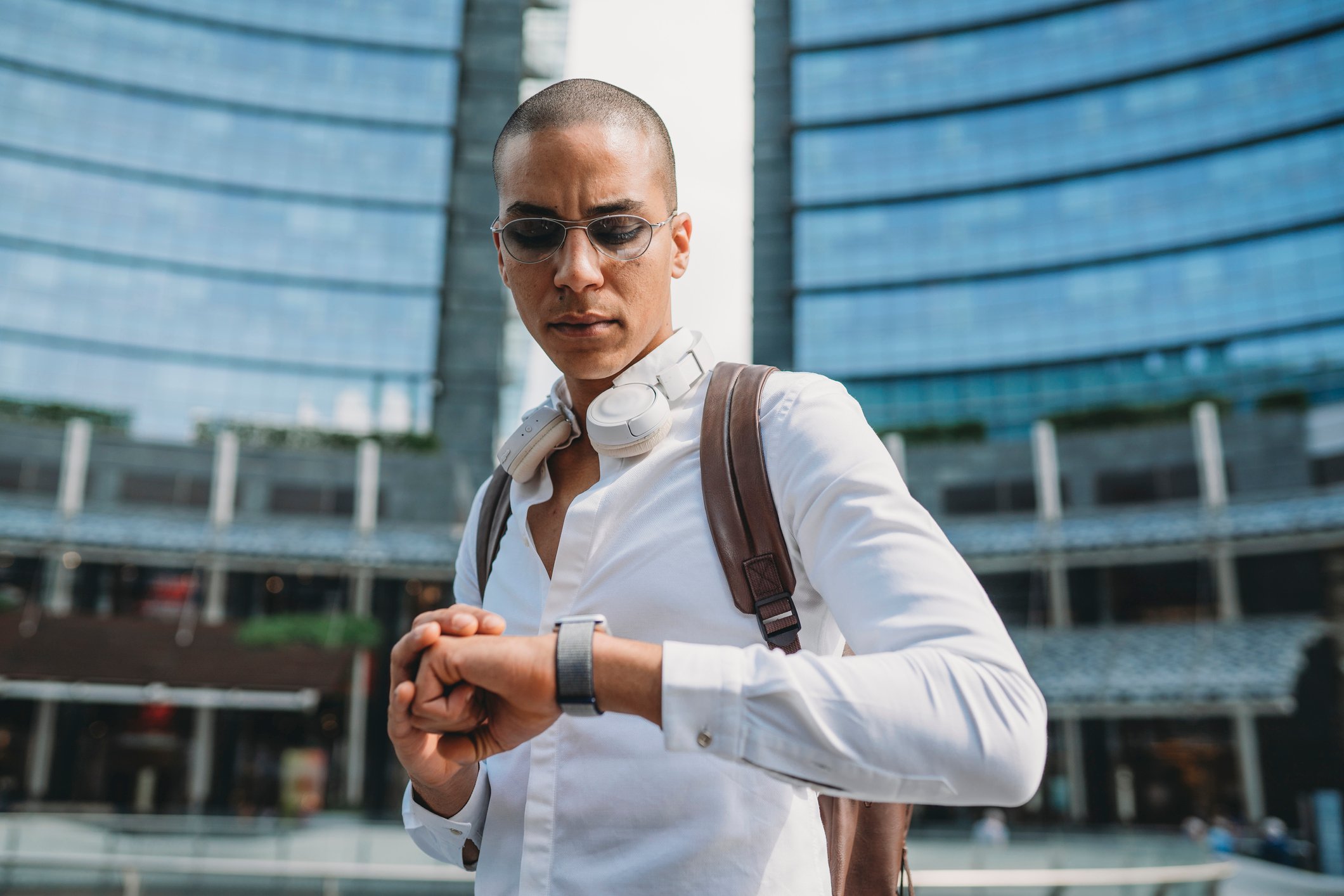A person stops on the street to check their wristwatch.