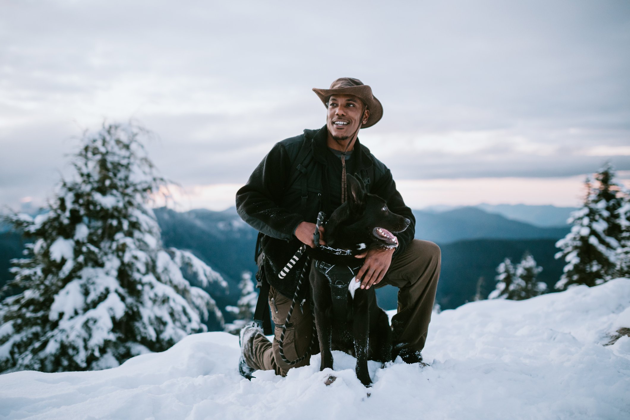 A person and a dog pause during a hike in the snow.