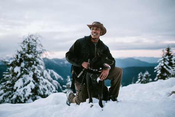 A person and a dog pause during a hike in the snow.
