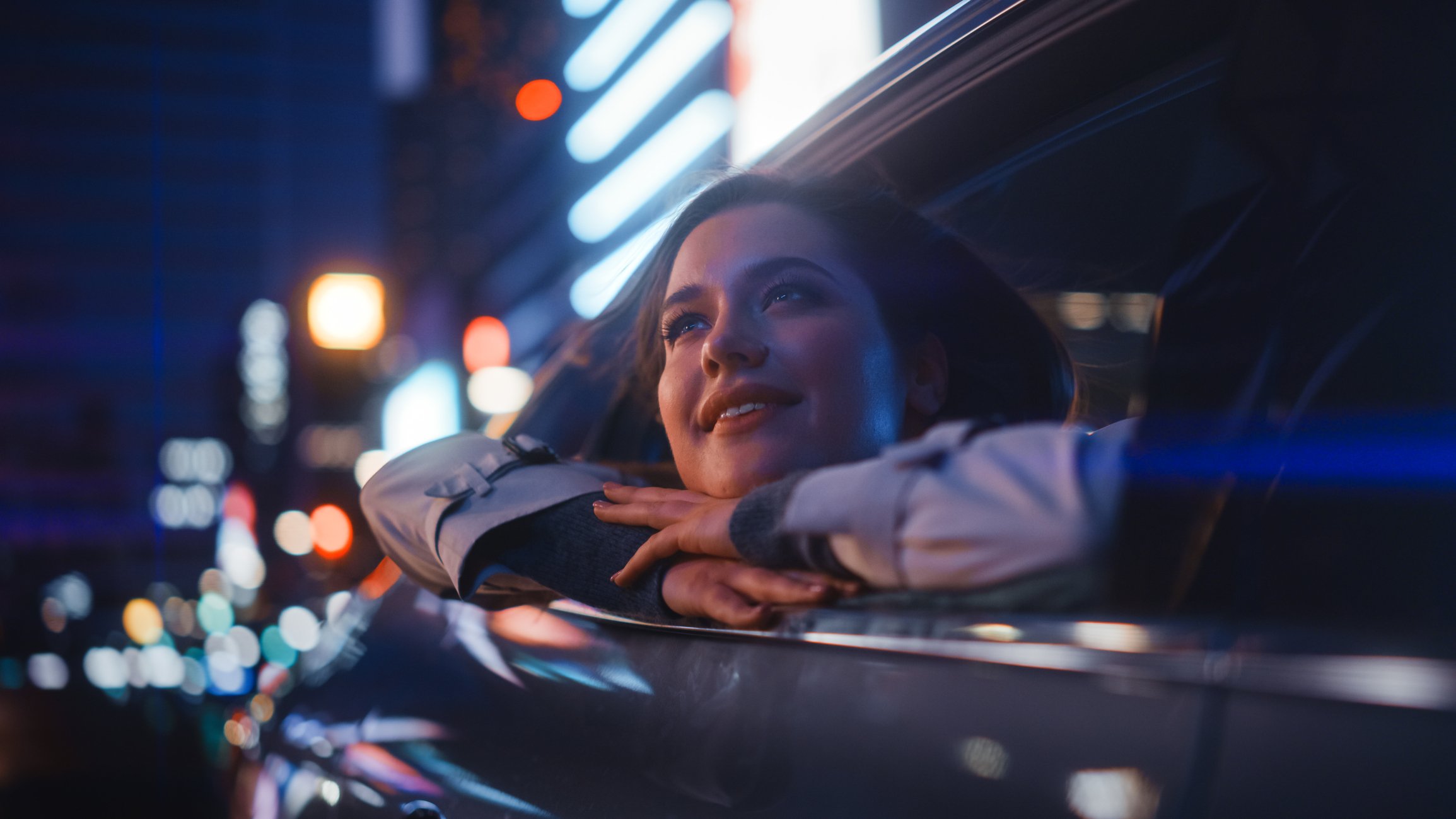 Person gazing out of a car window during a night ride in a city.