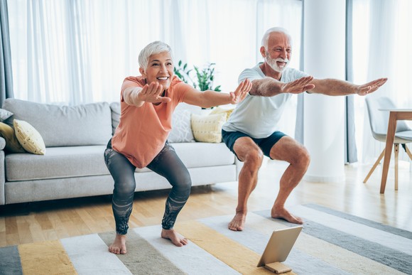 Two people practicing yoga at home.