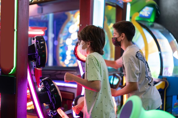 Two boys playing arcade games.