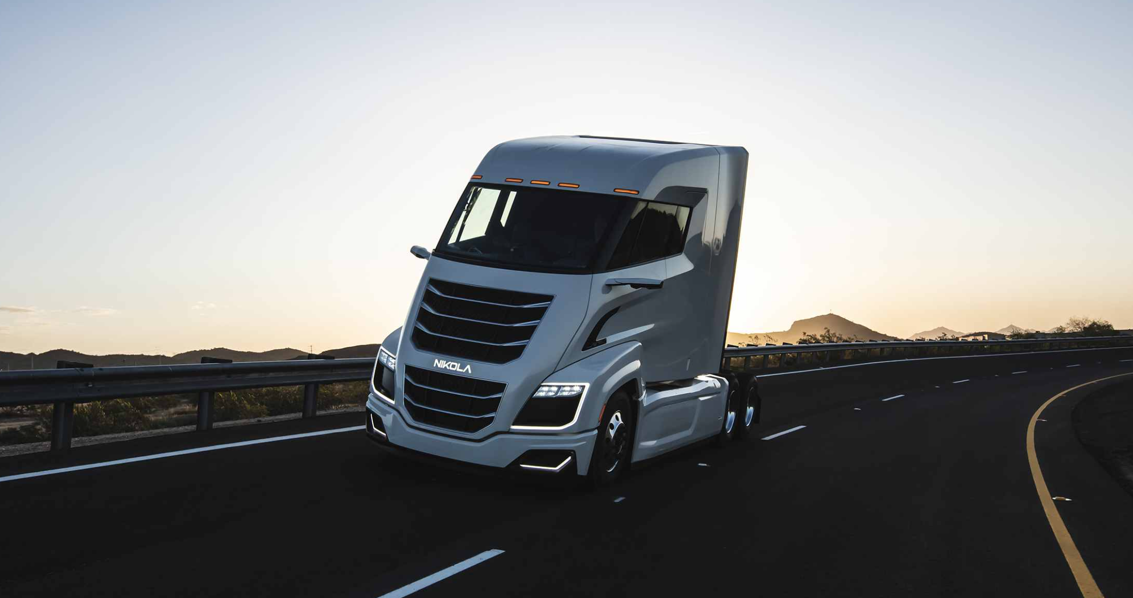 Nikola semi truck heading around bend on highway.