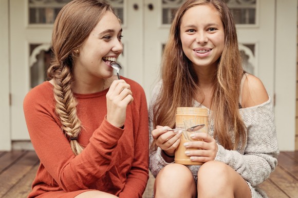 Two people eating peanut butter out of a jar.