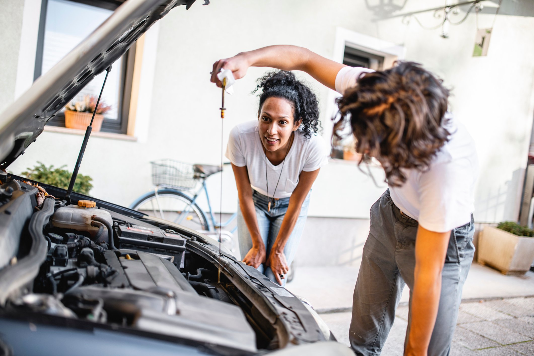 Two people check the oil in a car.