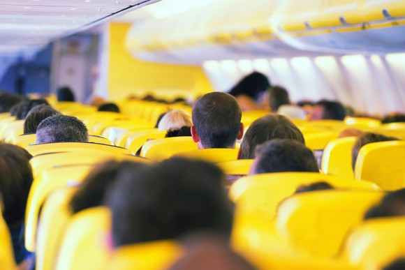 People fill seats in a crowded airplane.