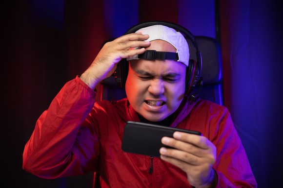 A frustrated mobile gamer looks at a smartphone.