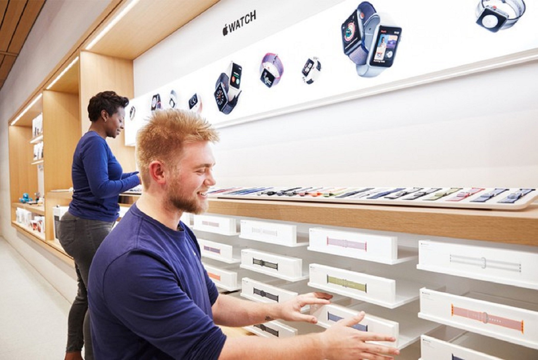 Two Apple store employees straightening Apple Watch display bands. 