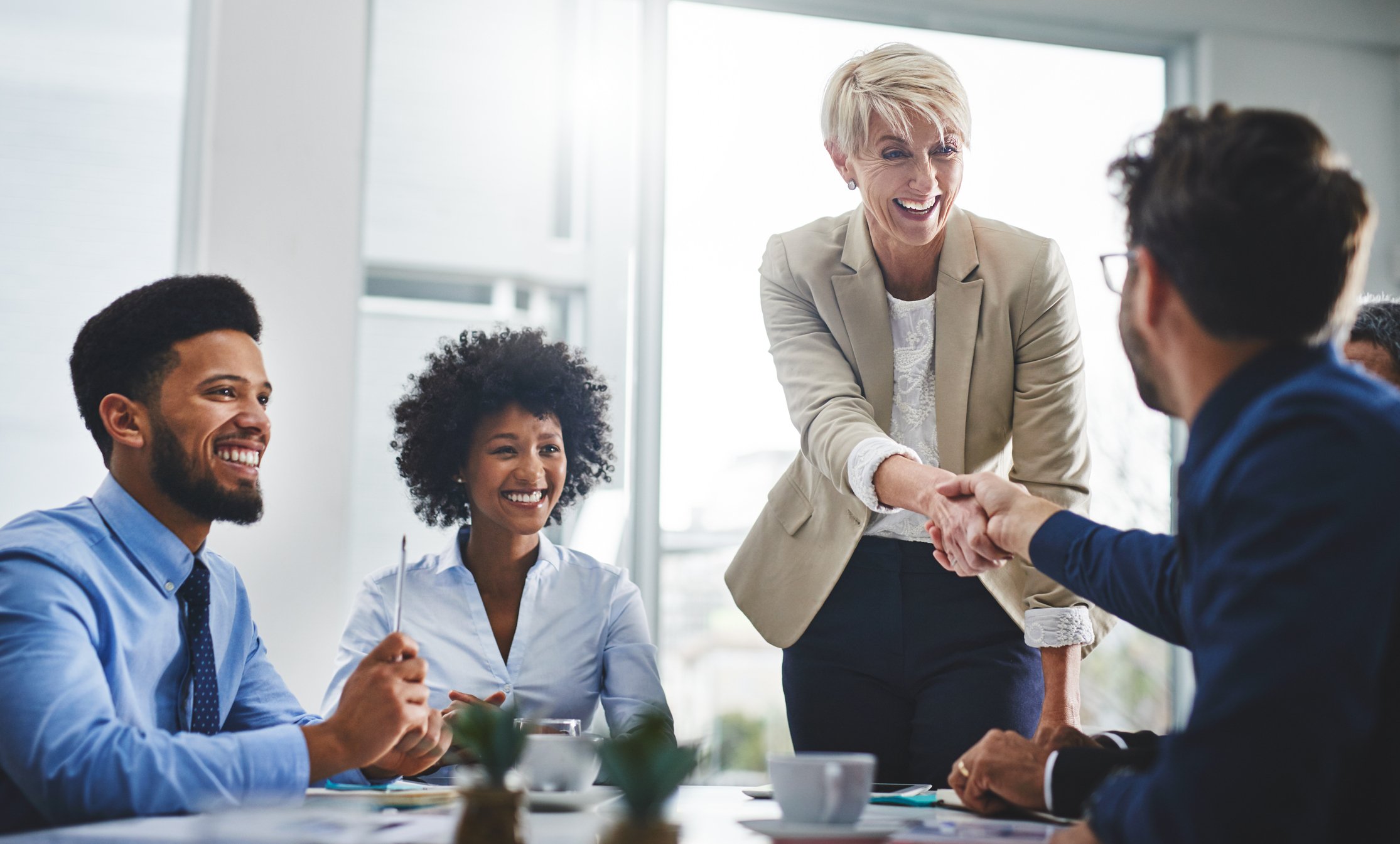 Four people in an office shaking hands.
