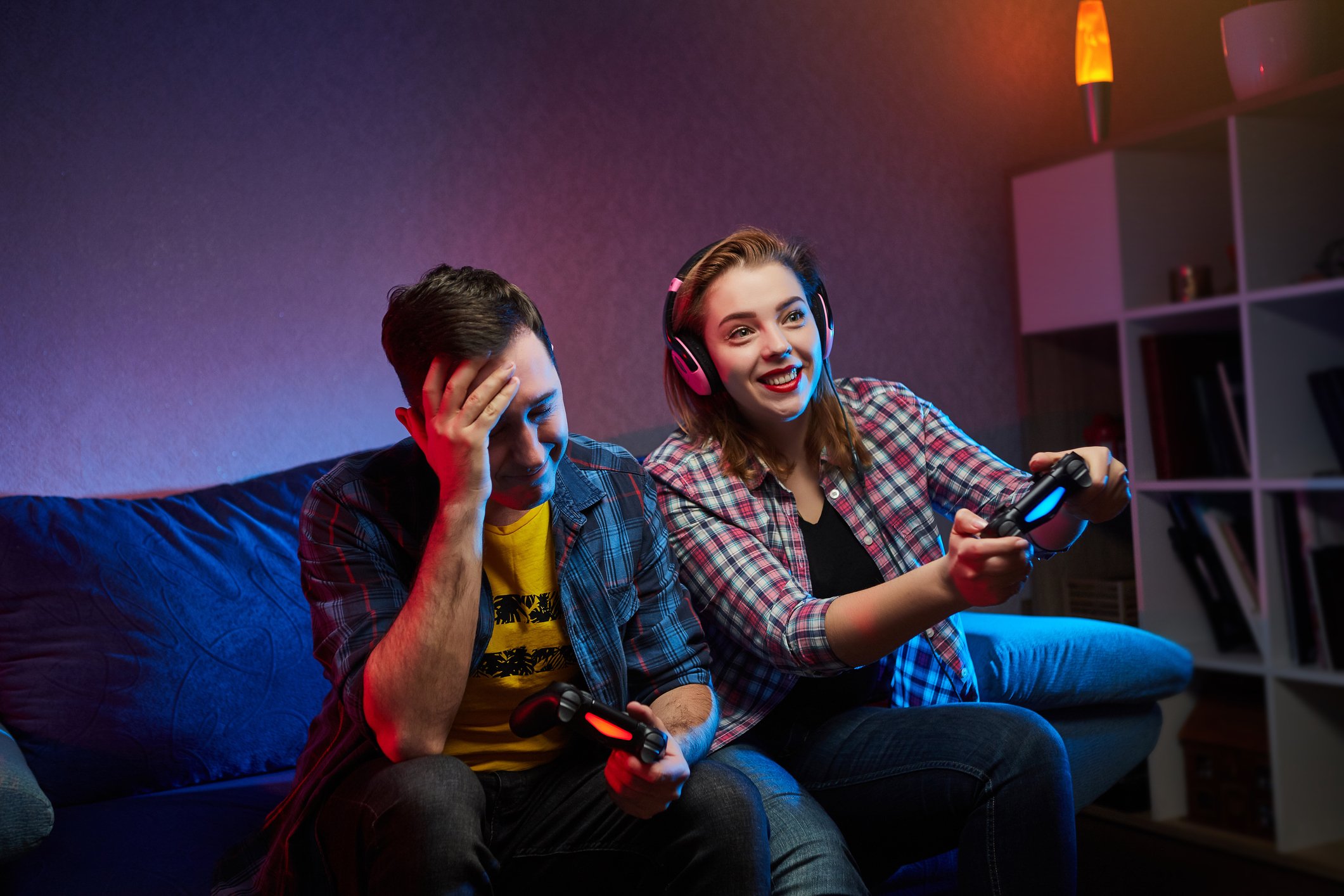 Two gamers playing on the same couch. One is clearly winning. The other one knows it.
