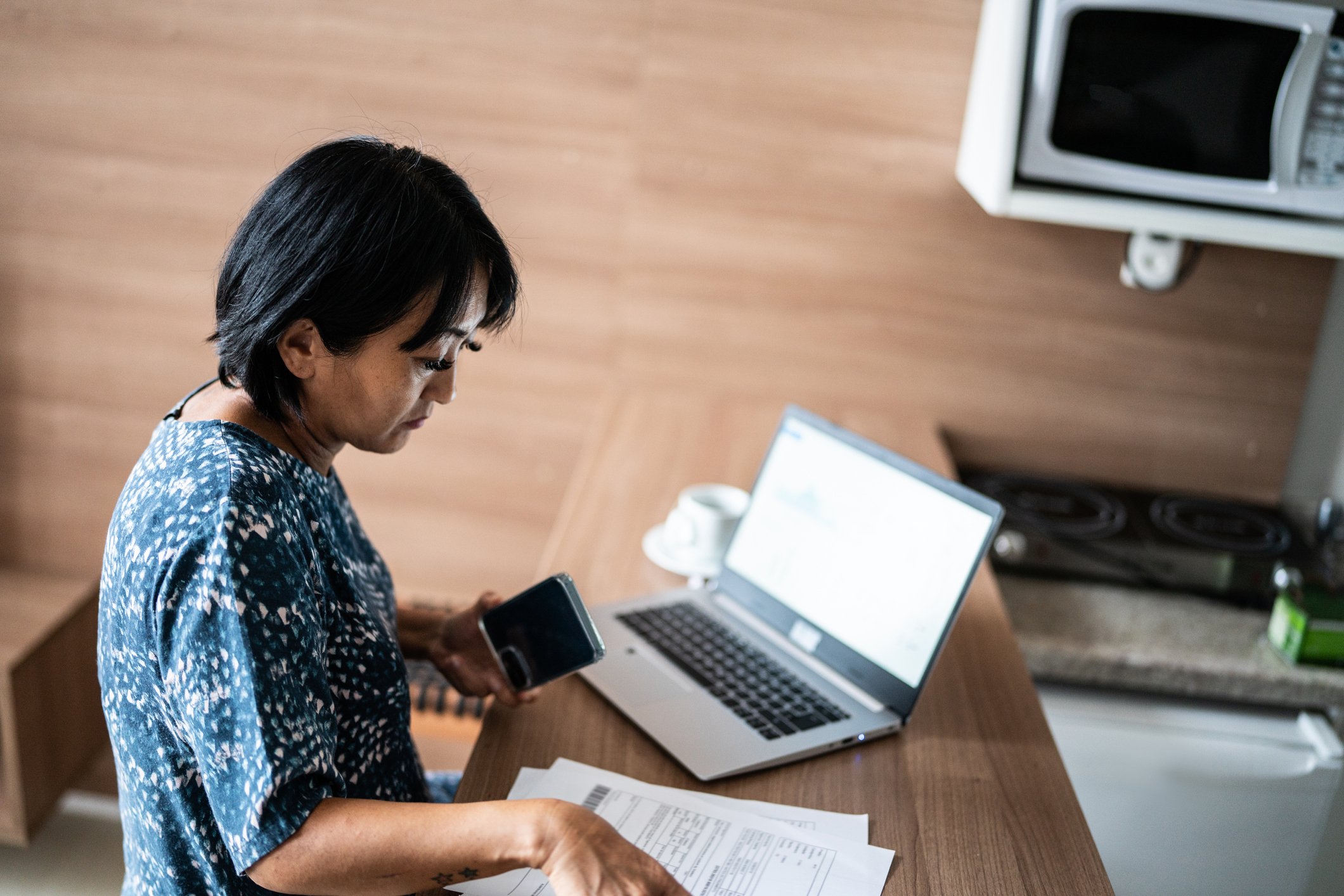 Person sitting at a desk with a laptop while studying financial documents.