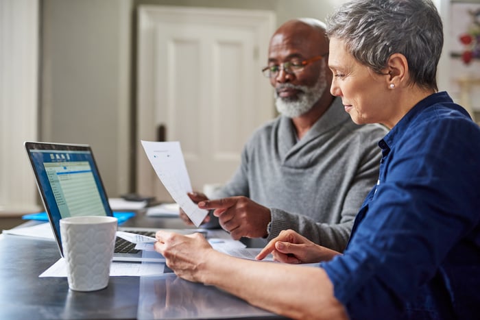 Two people reviewing their finances with laptop computer.