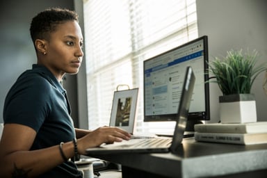 young person sitting at desk looking at laptop