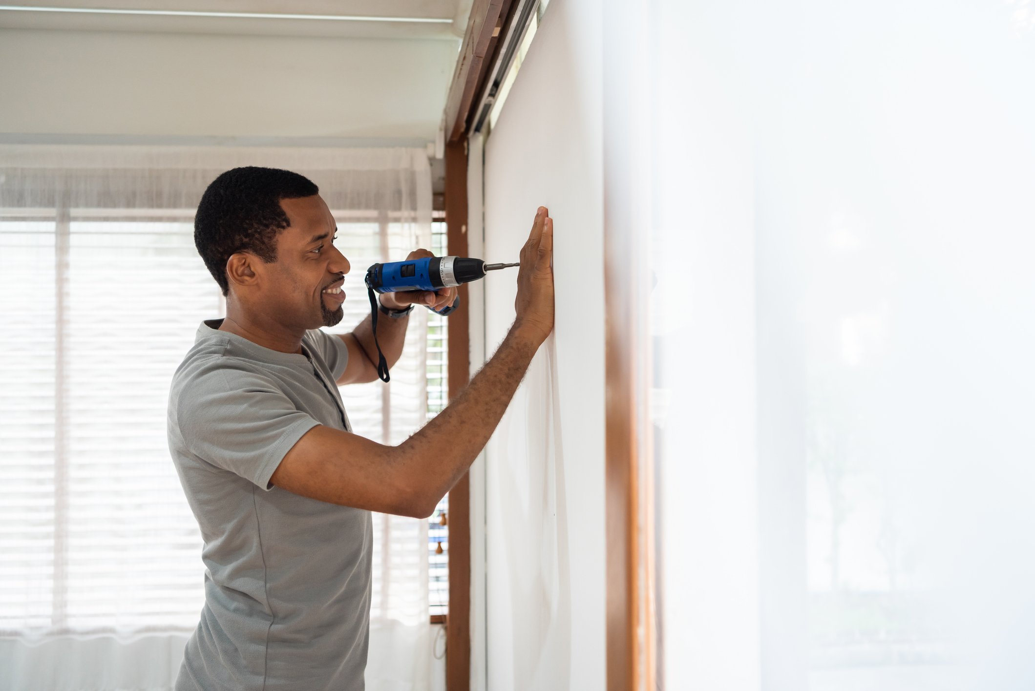 A person using a drill on a wall for a home improvement.